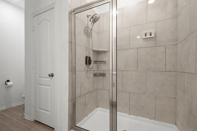 bathroom with baseboards, toilet, and a stall shower