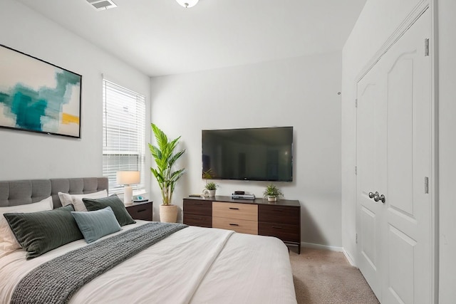 bedroom with a closet, baseboards, light colored carpet, and visible vents