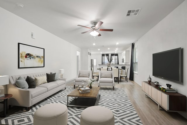 living area featuring visible vents, light wood-type flooring, and a ceiling fan