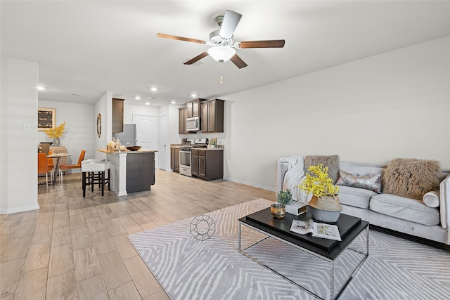 living area with recessed lighting, light wood-type flooring, baseboards, and ceiling fan