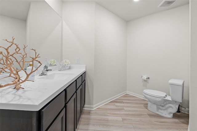 bathroom featuring visible vents, toilet, wood finished floors, baseboards, and vanity