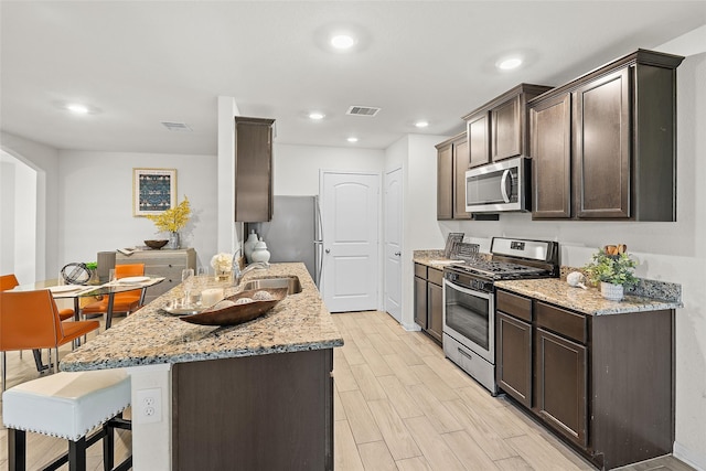 kitchen featuring visible vents, dark brown cabinets, appliances with stainless steel finishes, and wood tiled floor