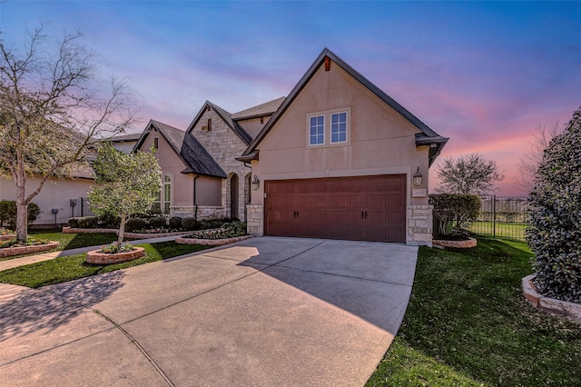 view of front facade with stucco siding, stone siding, concrete driveway, and fence