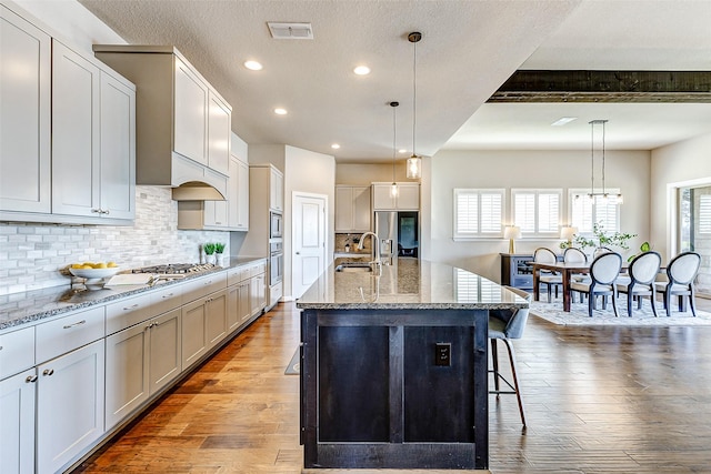 kitchen featuring visible vents, a breakfast bar, stainless steel appliances, a sink, and hardwood / wood-style flooring