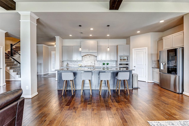 kitchen featuring dark wood finished floors, light stone counters, appliances with stainless steel finishes, and custom range hood