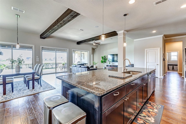 kitchen featuring a sink, visible vents, dark wood-style floors, and dark stone counters