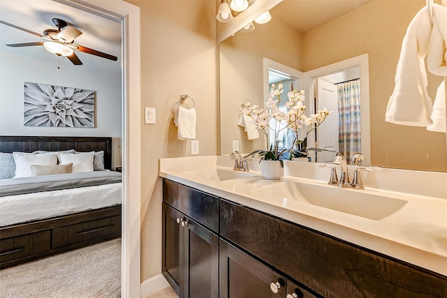 ensuite bathroom featuring double vanity, connected bathroom, ceiling fan, and a sink