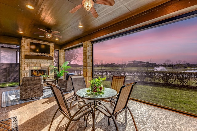 view of patio / terrace with an outdoor stone fireplace, outdoor dining space, and a ceiling fan