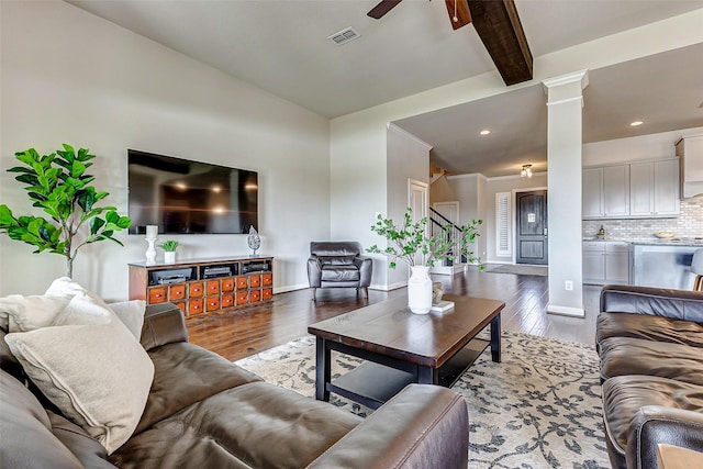 living area with visible vents, decorative columns, a ceiling fan, and wood finished floors