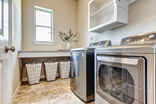 clothes washing area with laundry area, washer and dryer, and baseboards