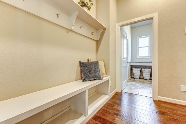 mudroom featuring baseboards, dark wood-style floors, and a textured wall