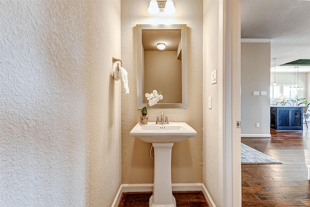 bathroom featuring a textured wall, baseboards, and hardwood / wood-style flooring