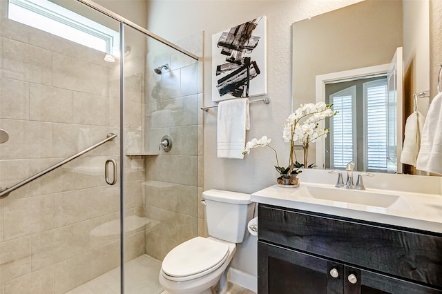 bathroom featuring toilet, a stall shower, and vanity