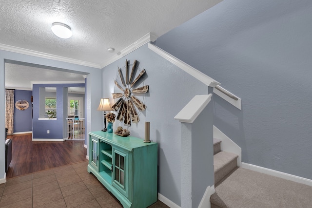 stairs featuring crown molding, baseboards, tile patterned floors, and a textured ceiling