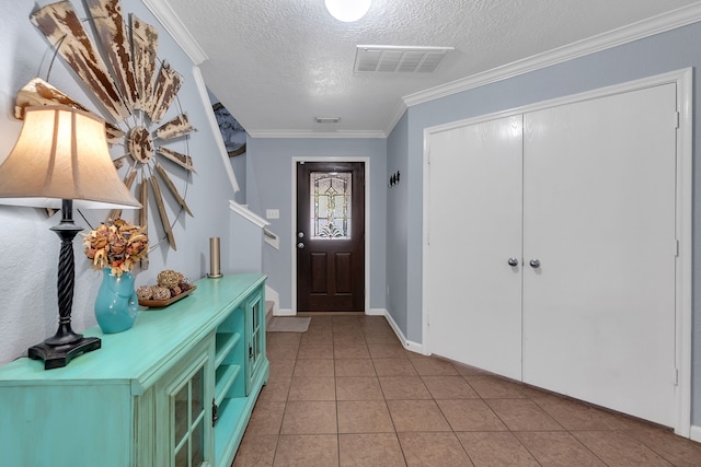 foyer entrance with light tile patterned floors, baseboards, visible vents, a textured ceiling, and crown molding