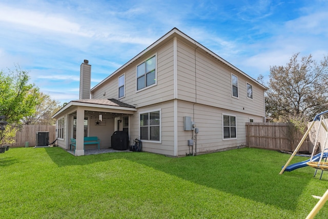 rear view of house featuring a yard, a fenced backyard, cooling unit, and a chimney