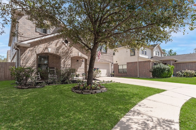 view of front facade featuring a front yard, concrete driveway, fence, and brick siding