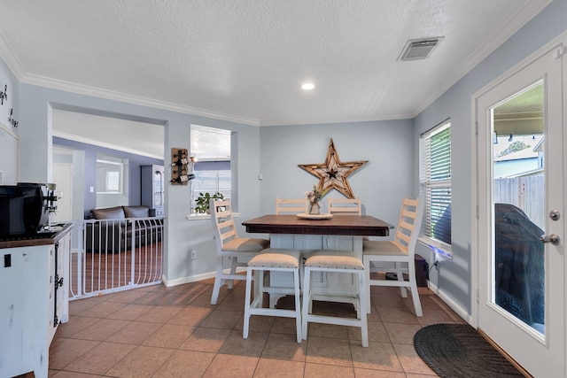 dining area with light tile patterned floors, visible vents, baseboards, and crown molding