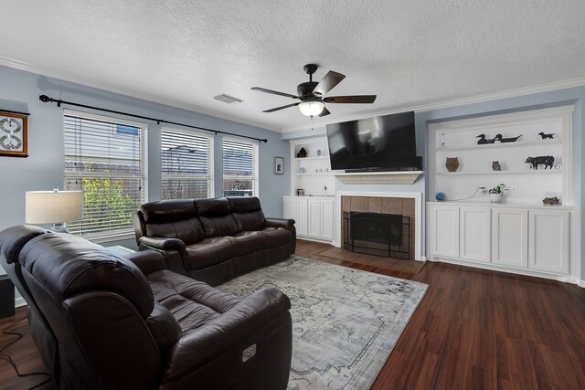 living area with visible vents, a textured ceiling, dark wood finished floors, crown molding, and ceiling fan