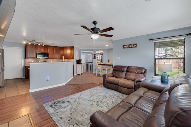 living room with wood finished floors, a textured ceiling, and ceiling fan