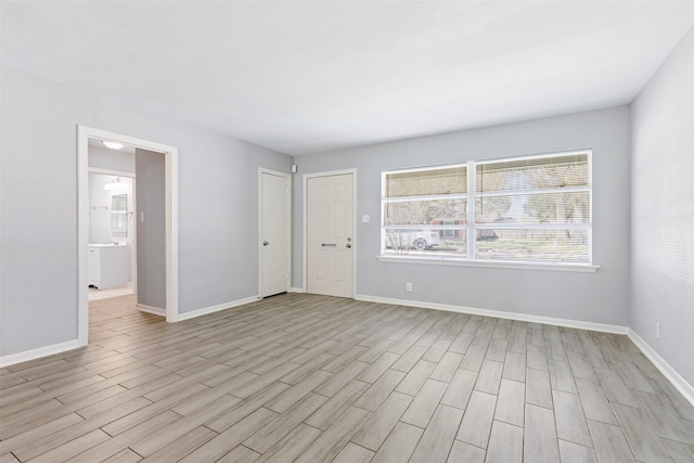 empty room featuring baseboards and light wood-type flooring