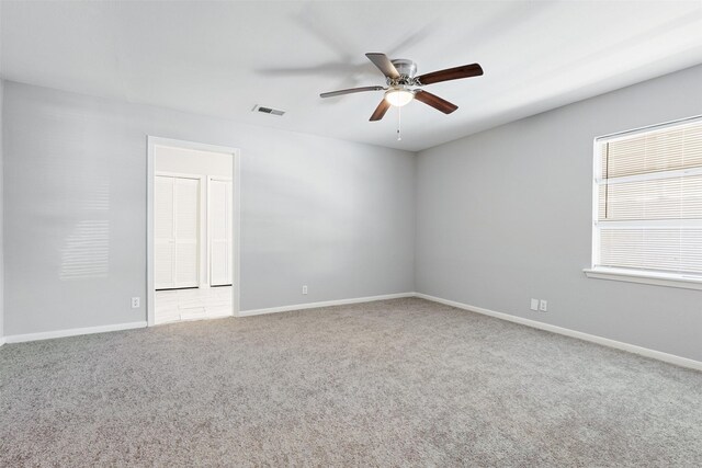 unfurnished room with baseboards, visible vents, carpet floors, and ceiling fan