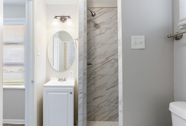 bathroom featuring a marble finish shower, toilet, and vanity