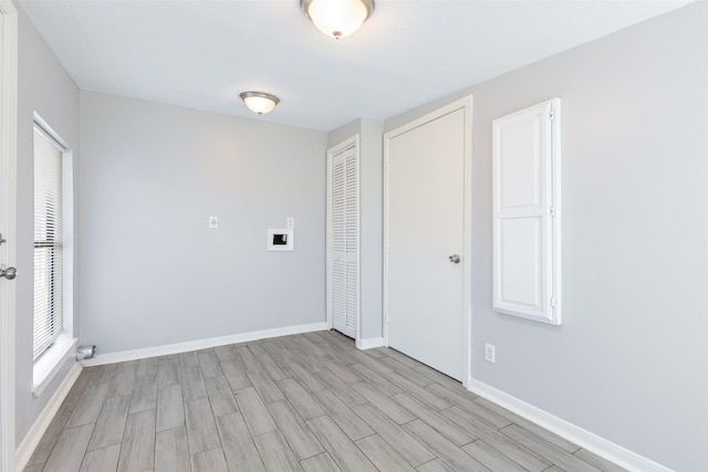 spare room featuring light wood finished floors, a wealth of natural light, and baseboards