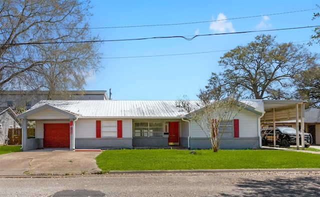 ranch-style home featuring metal roof, driveway, a garage, and a front lawn