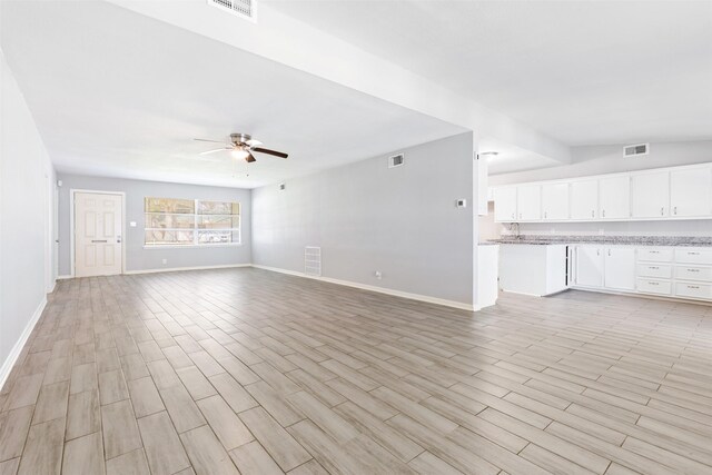 unfurnished living room featuring light wood finished floors, visible vents, baseboards, and a ceiling fan