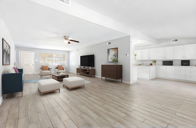 unfurnished living room with a sink, visible vents, baseboards, and ceiling fan