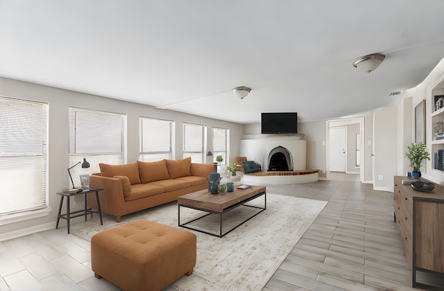 living area with baseboards and a fireplace with raised hearth