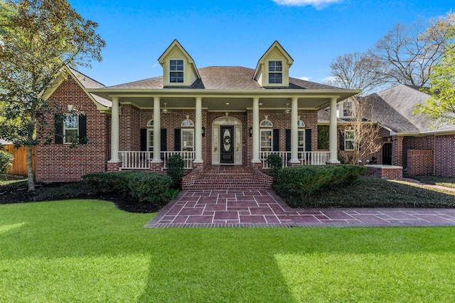 view of front of house featuring brick siding, covered porch, and a front yard