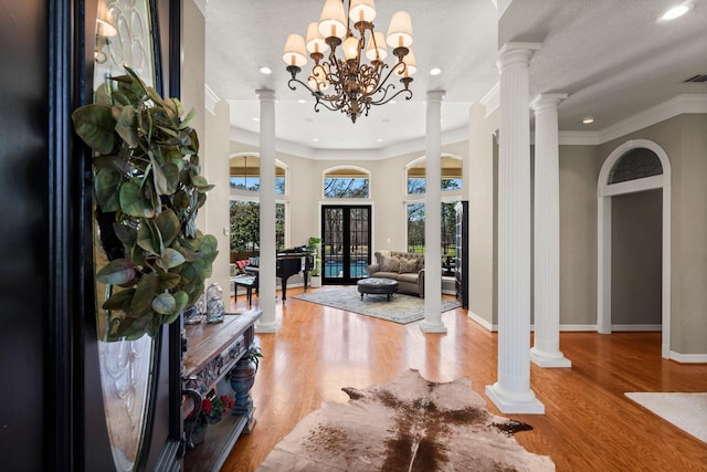 entrance foyer with ornamental molding, baseboards, ornate columns, and wood finished floors