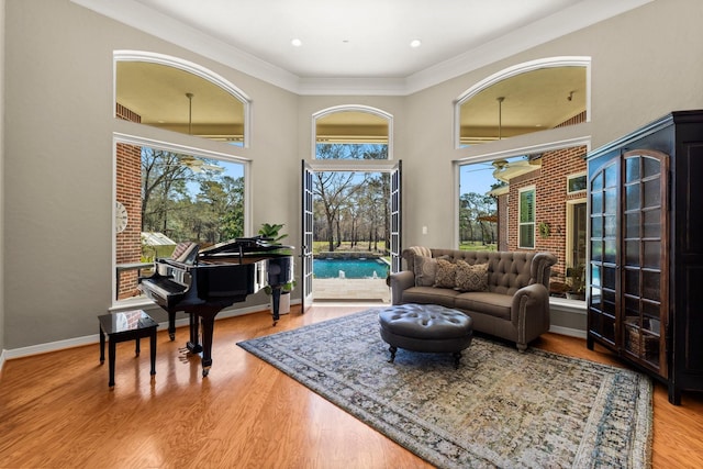 living room with baseboards, a high ceiling, wood finished floors, and crown molding