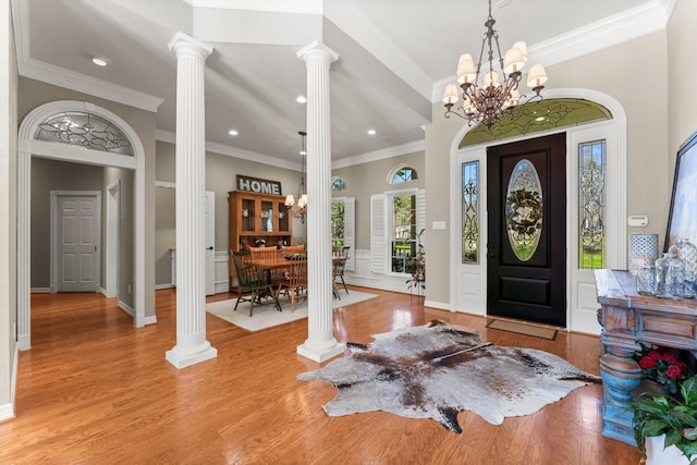 foyer with light wood-type flooring, an inviting chandelier, crown molding, and ornate columns