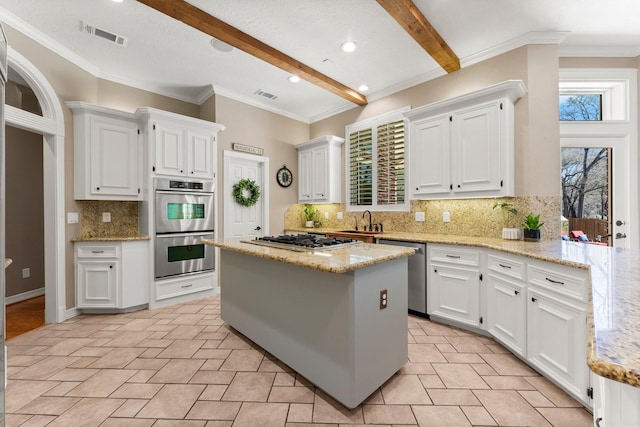 kitchen with beamed ceiling, visible vents, a sink, stainless steel appliances, and white cabinets