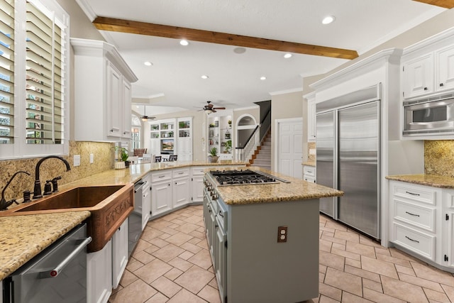 kitchen featuring built in appliances, beamed ceiling, white cabinets, and ceiling fan