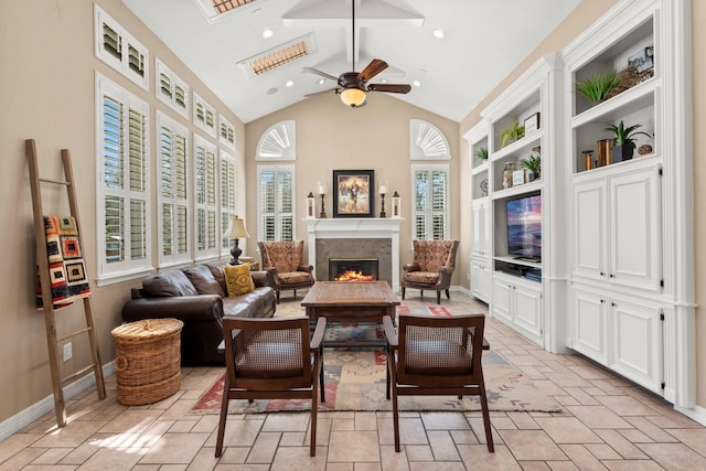 living area with ceiling fan, a lit fireplace, recessed lighting, stone tile flooring, and high vaulted ceiling