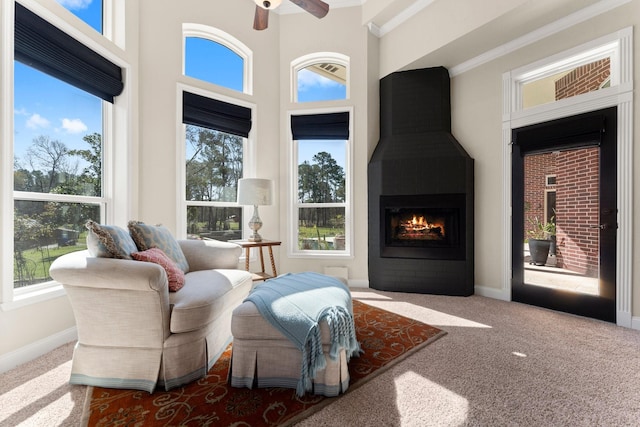 sitting room featuring a high ceiling, carpet flooring, a fireplace, baseboards, and ceiling fan