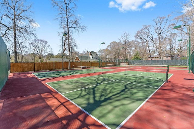 view of tennis court featuring community basketball court and fence