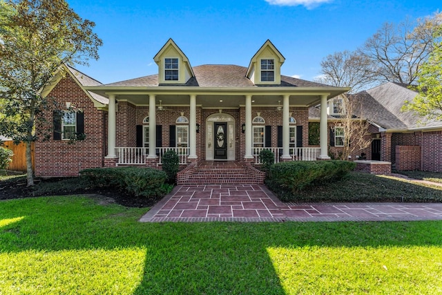 view of front of house with brick siding, covered porch, and a front yard