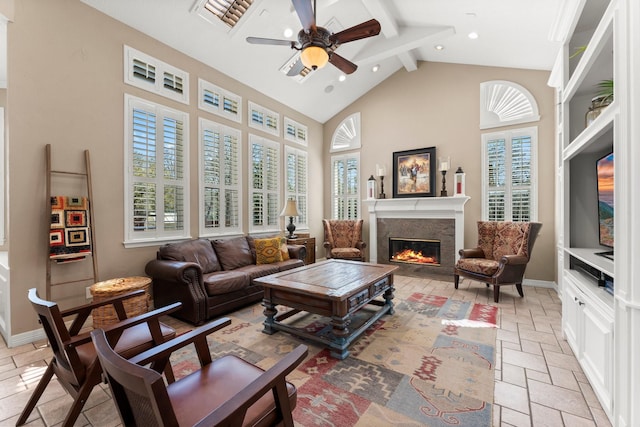 living area with beam ceiling, high vaulted ceiling, stone tile floors, a high end fireplace, and ceiling fan