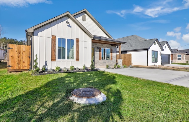 modern farmhouse featuring board and batten siding, a front lawn, and fence