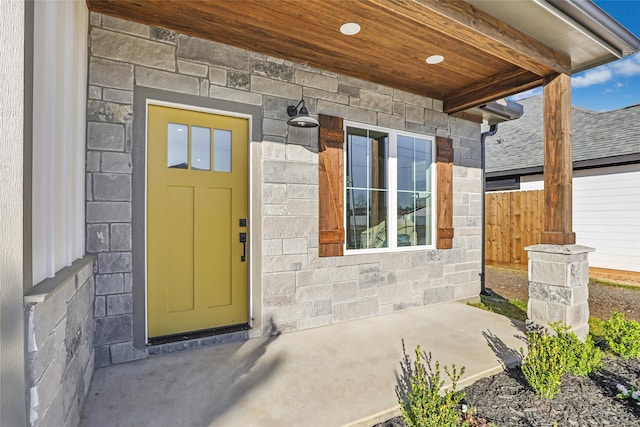 entrance to property with stone siding and fence