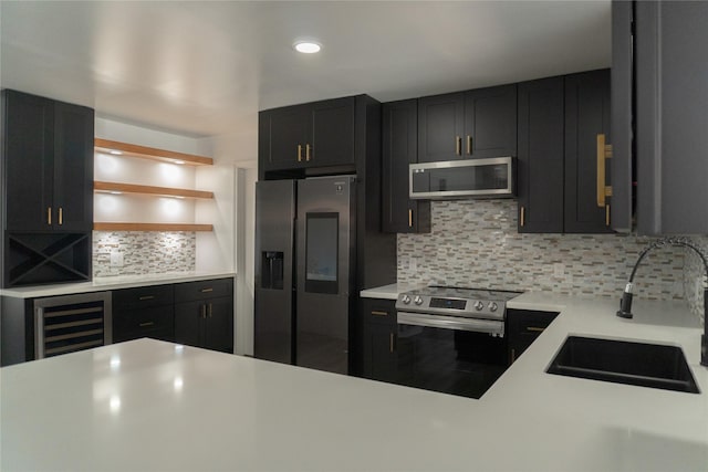 kitchen with a sink, wine cooler, appliances with stainless steel finishes, light countertops, and dark cabinets