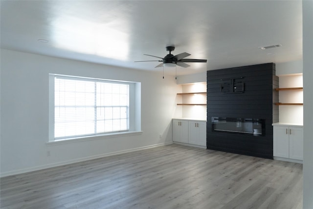 unfurnished living room with light wood-type flooring, visible vents, a fireplace, baseboards, and ceiling fan