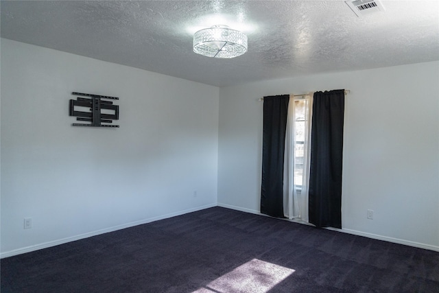 empty room featuring baseboards, visible vents, dark carpet, and a textured ceiling