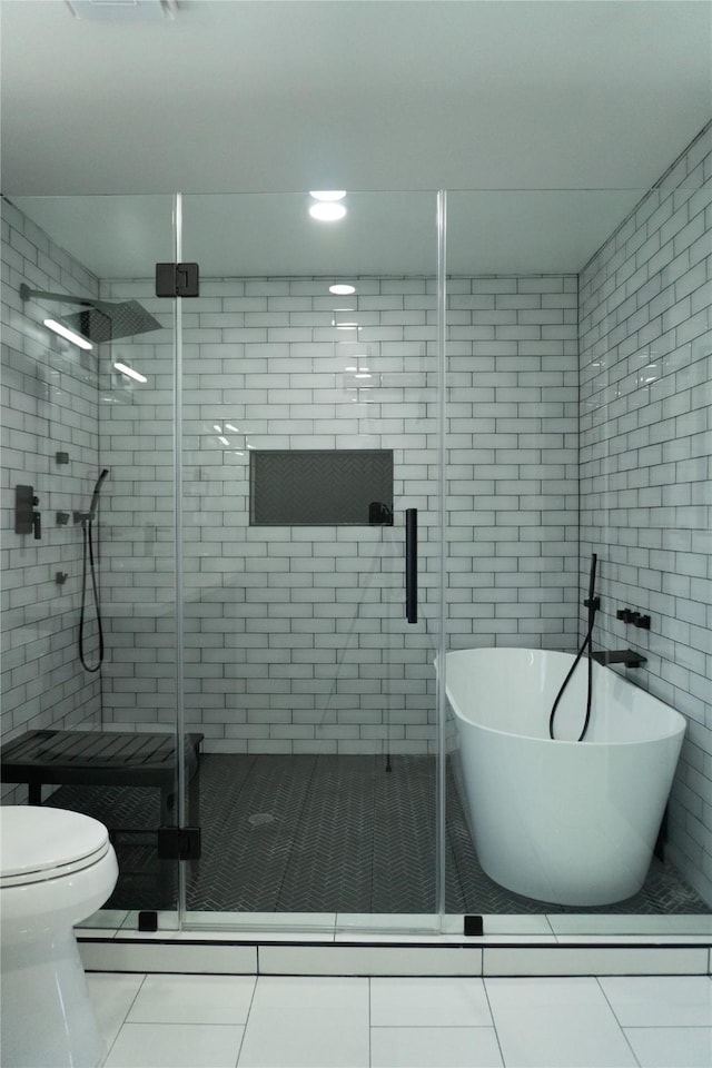 full bath featuring tile patterned flooring, a shower stall, a freestanding tub, and toilet