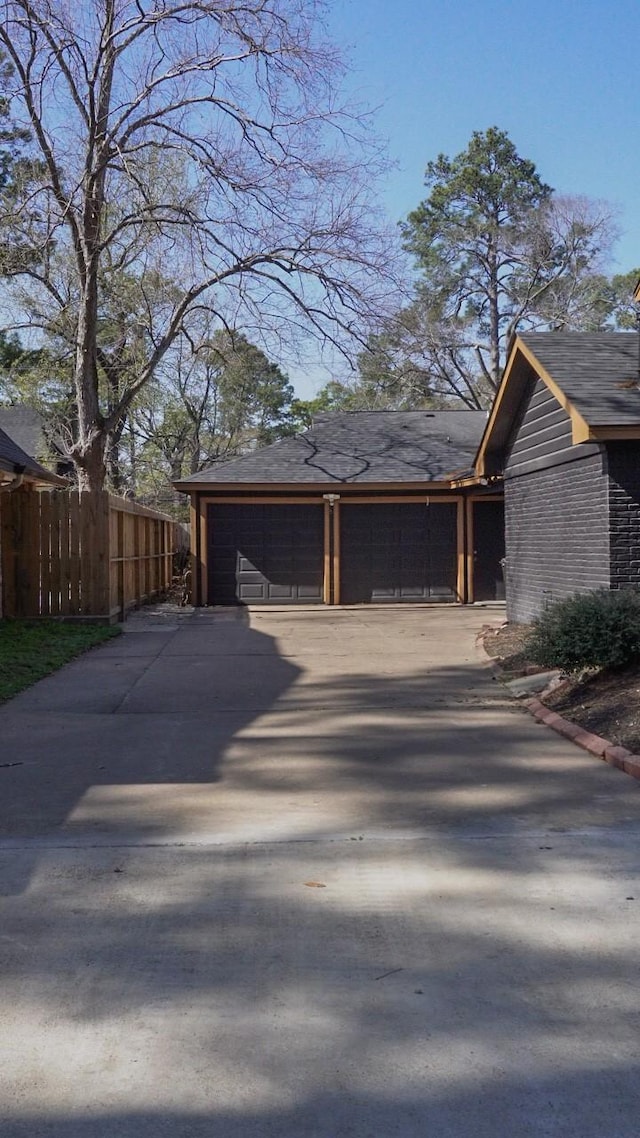 view of home's exterior featuring concrete driveway, an attached garage, and fence